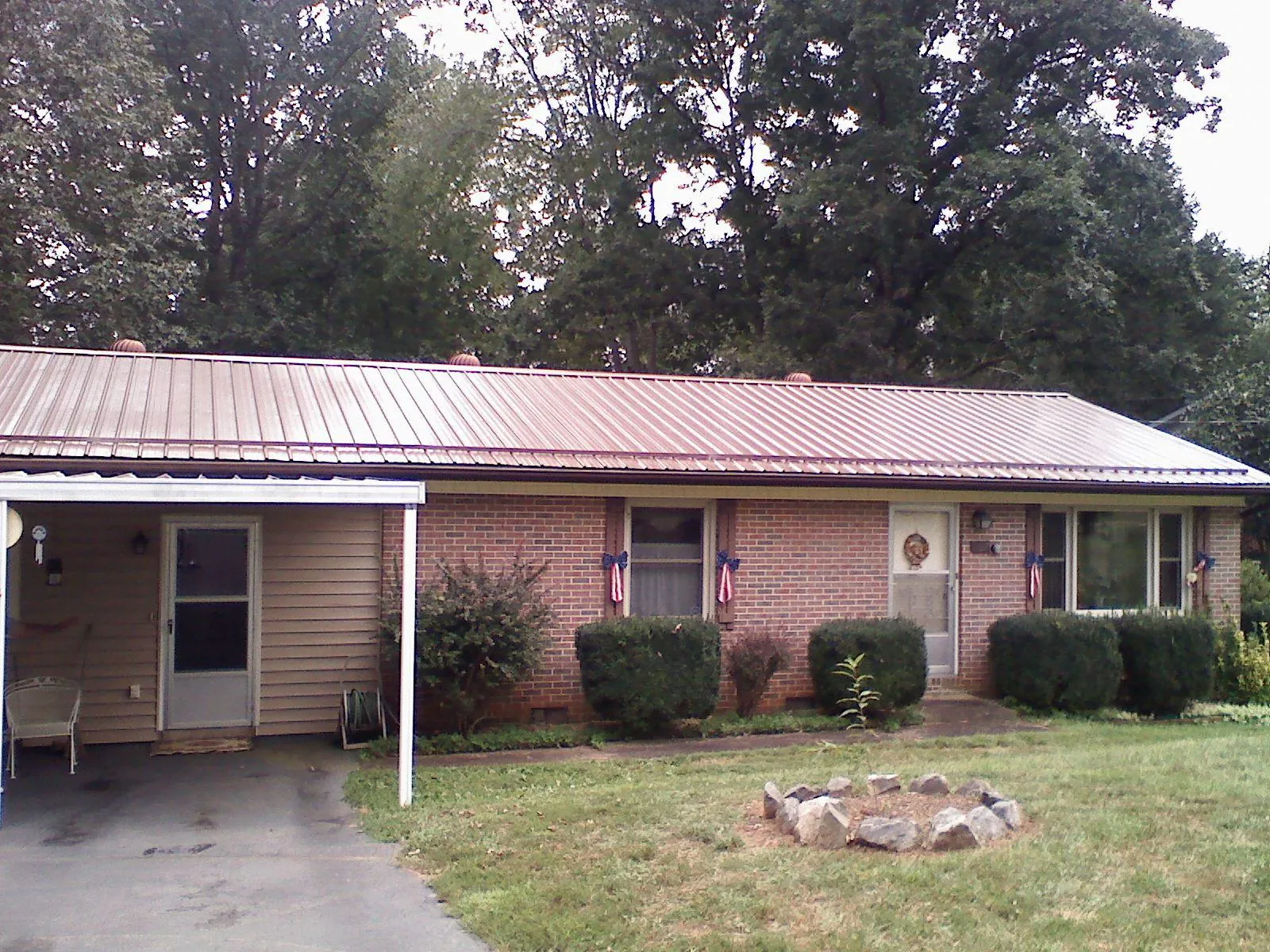 Bronze metal roof and carport on a brick ranch home — Roof Repair work by our crew in Lamar