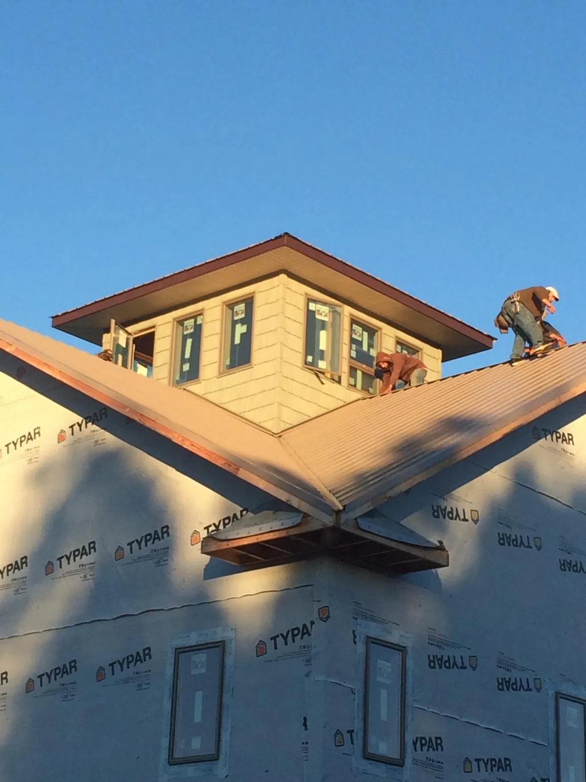 Roofers working around a rooftop cupola on a new metal roof at sunset — Roof Waterproofing in Lamar by Roofing Brothers